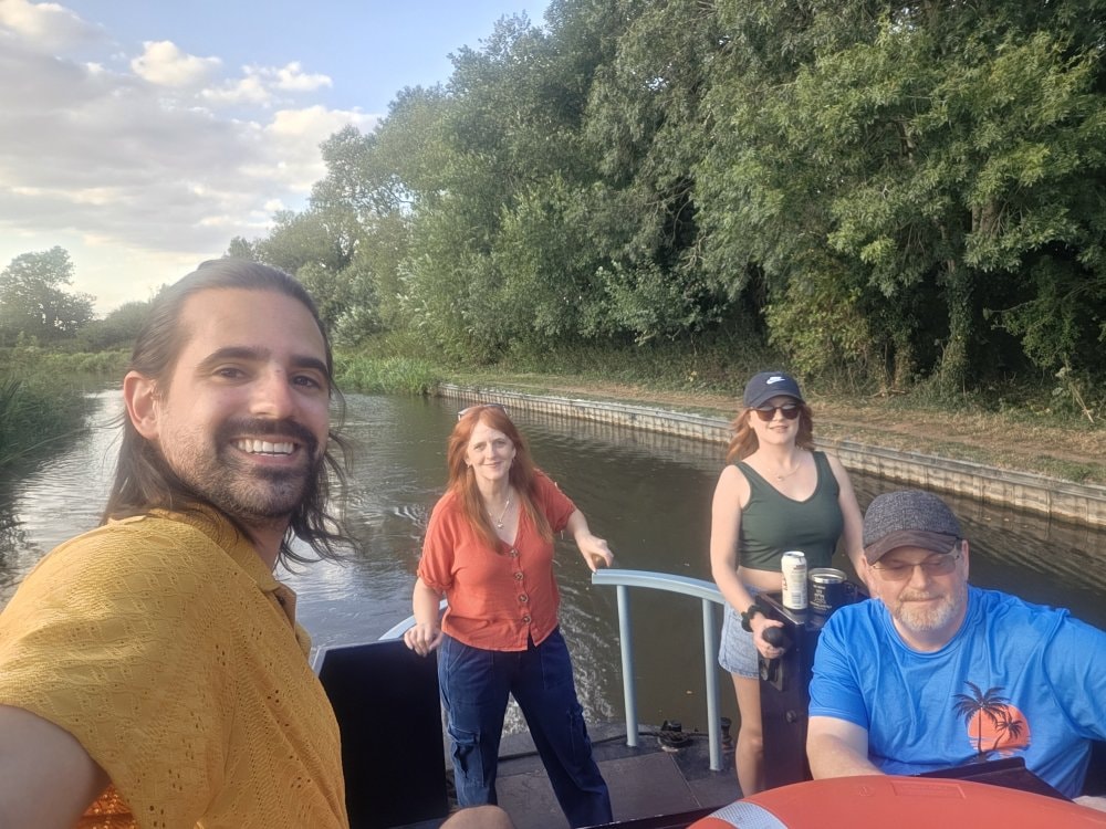 Four friends relaxing on the deck of a narrowboat on a summer evening
