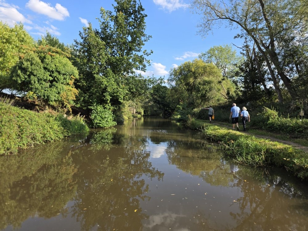 People walking along a scenic canal towpath in summer